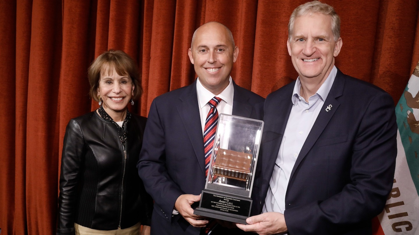 USC President Carol Folt (L) and Provost Andrew Guzman (R) present Andy Call with his &quot;chair&quot; — a miniature replica of the Alan Casden Dean’s Chair, symbolic of the title that he now holds.[USC Photo/Steve Cohn]