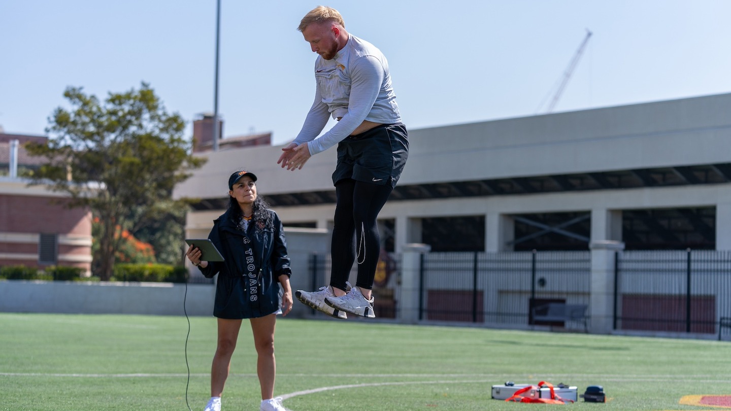 Student Nick Adgar performs vertical jump as Professor Lorena Martin take data measurements