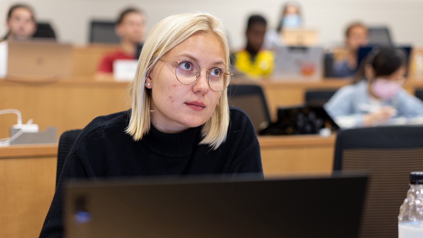Female-presenting student in a lecture hall.