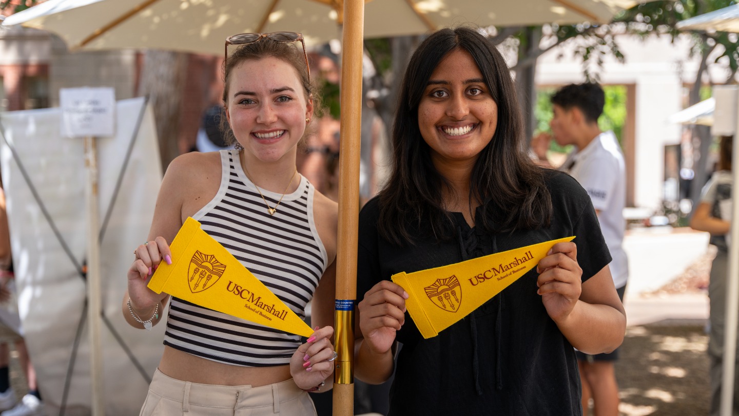 students holding USC Marshall pennants