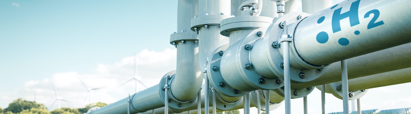 Color photograph of an H2 pipeline with wind energy in the background