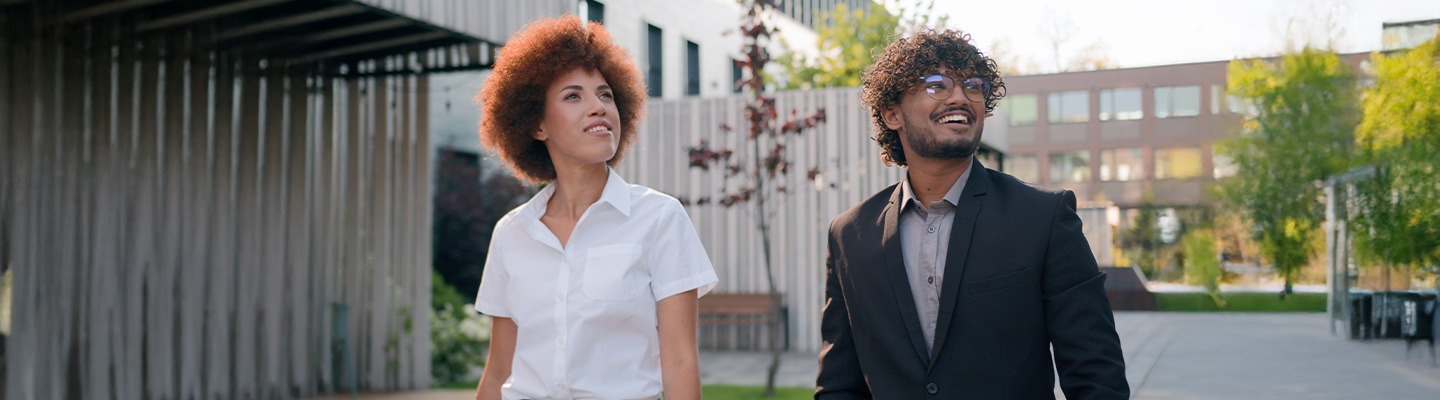 Two grad students walking outdoors on a sunny day.