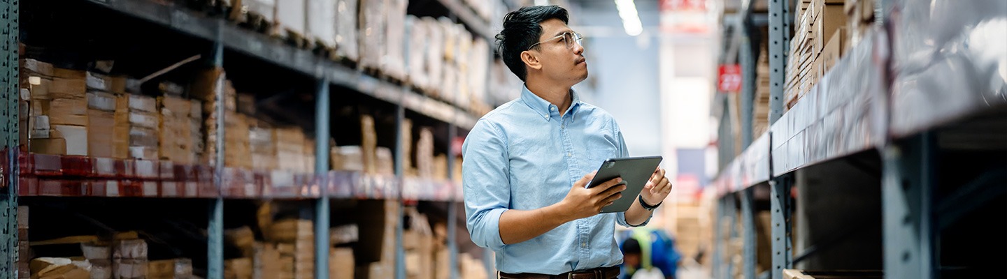 A male-presenting graduate student with a digital tablet in a warehouse.