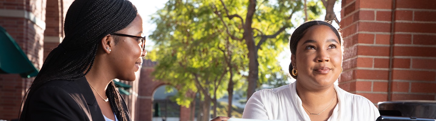 Two women working on tablets outside on the USC campus.