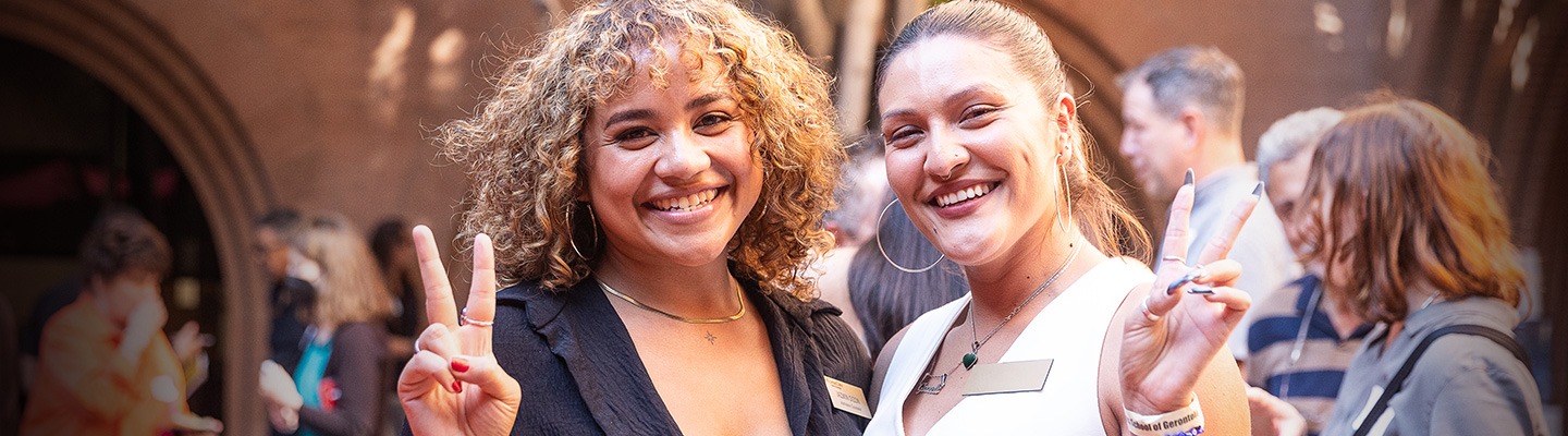 Two women smiling and flashing the "Fight On!" sign.