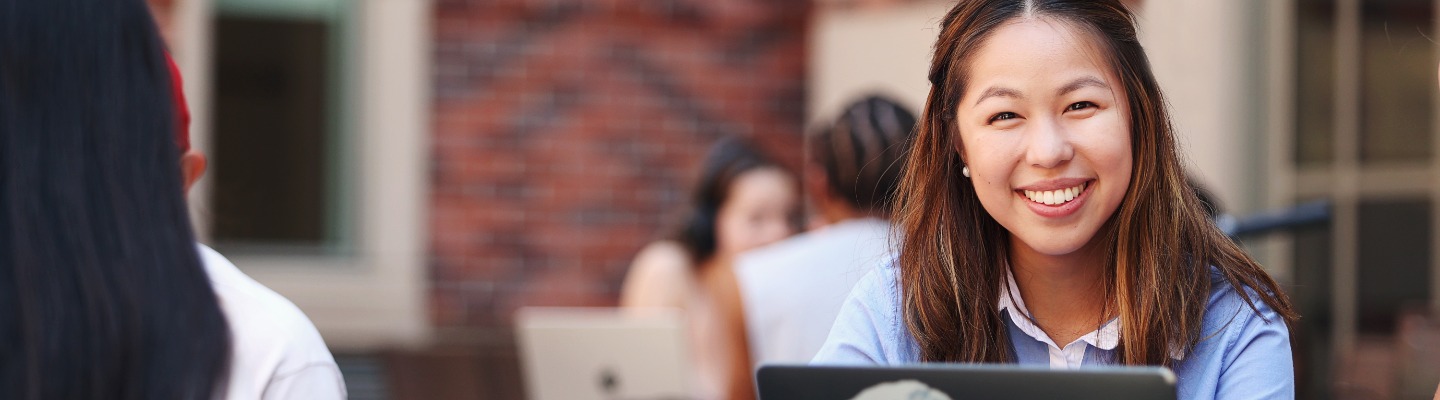 Student sitting outside smiling towards the camera