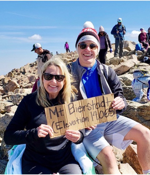 Color photograph of two people holding a sign reading "Mt. Bierstadt (Elevation 14,065).