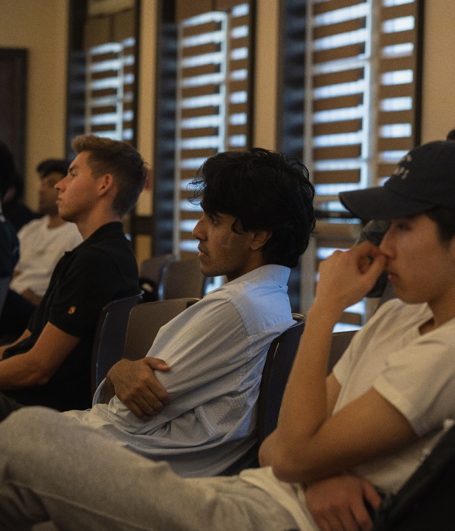 three students listening in a dimly lit room