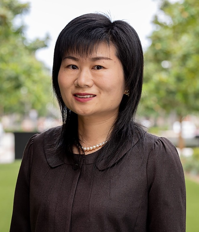 Asian woman wearing pearls and a suit standing outdoors