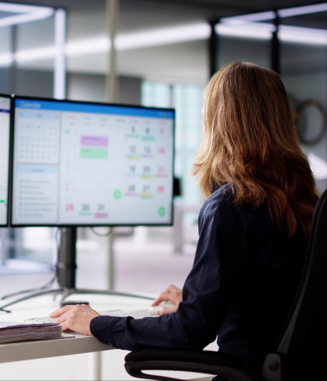 Woman sitting in front of monitors looking at data