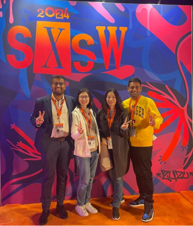 Students taking a picture in front of a SXSW banner