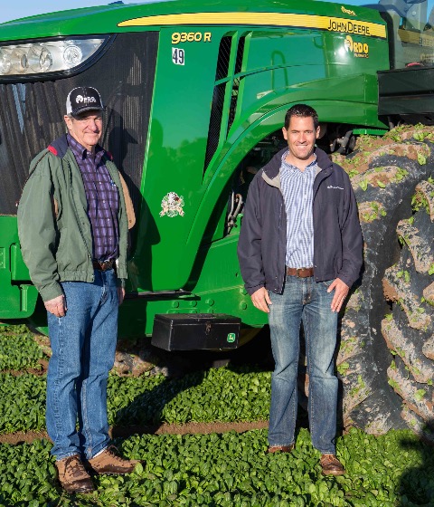 Two Men Standing By a Green Tractor