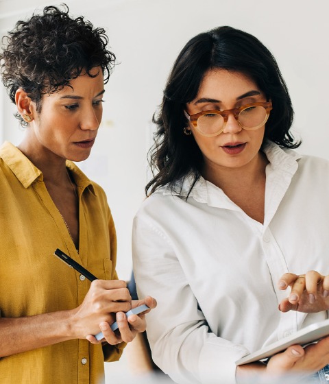 Color photograph of two coworkers reviewing work on an iPad.