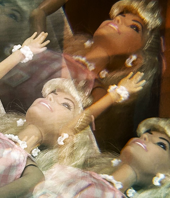A Barbie doll waving towards the sky.