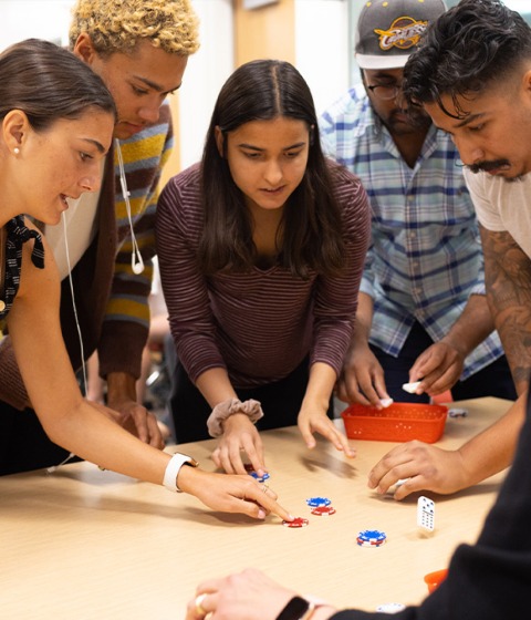 Indoor, color photograph of five students working together on a group project at USC.