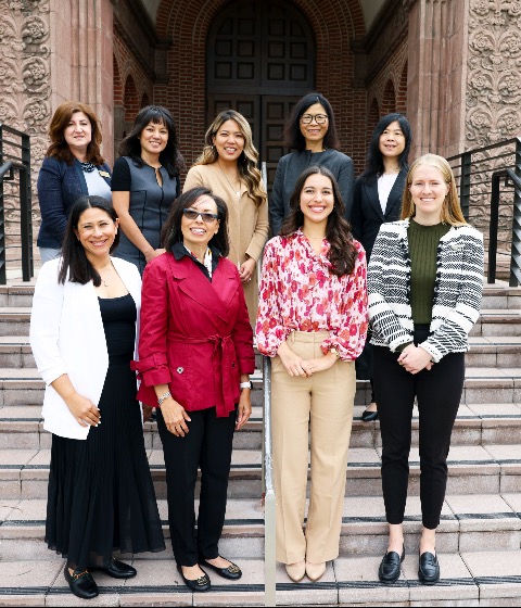 Color photo featuring a group of diverse women standing on the stairs of a USC building.