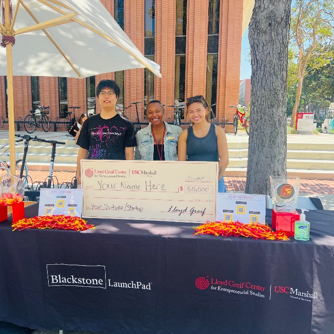Three smiling students hold jumbo check