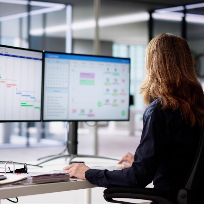 an employee sitting at two computer monitors