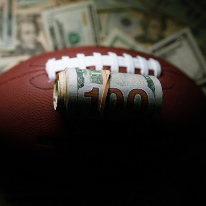 roll of hundred dollar bills on a football