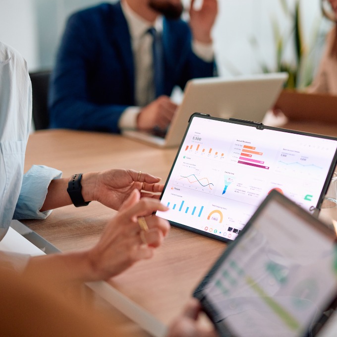 People sitting around a table with a tablet in the middle showing data