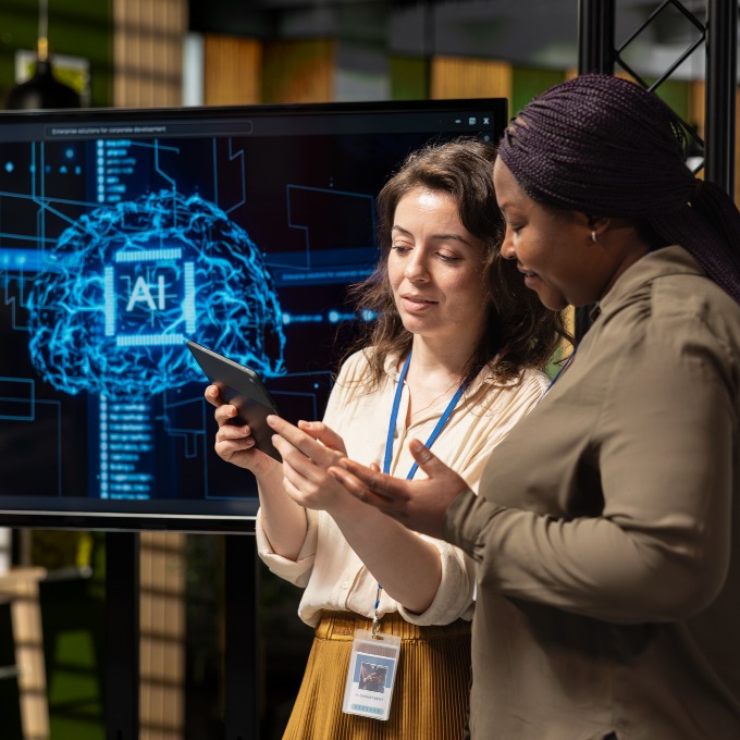 two employees working with AI on a tablet