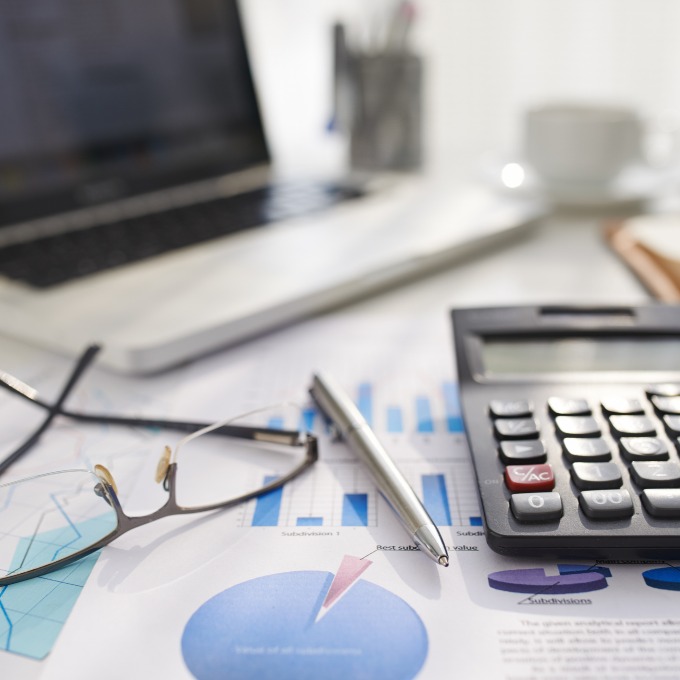 glasses and calculator sitting on graphs