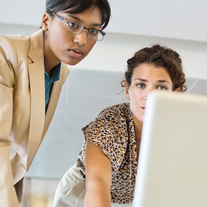 Color photograph of two people looking at a computer screen.
