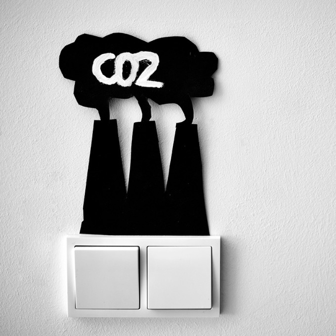 Wall switch with cutout refinery towers billowing CO2.