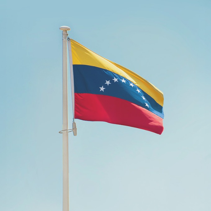The flag of Venezuela flying amidst a clear blue sky.
