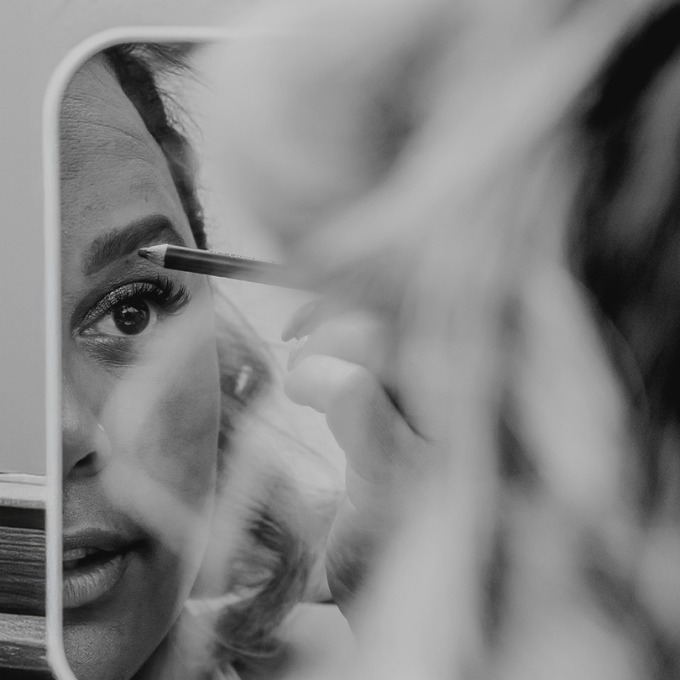 A female-presenting person applying make-up.