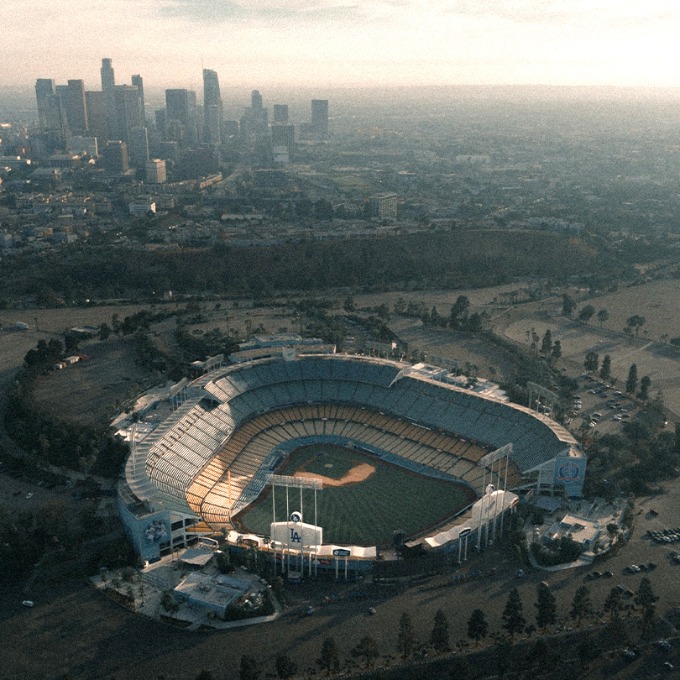 Color aerial photograph of Dodger Stadium with downtown Los Angeles in the background.