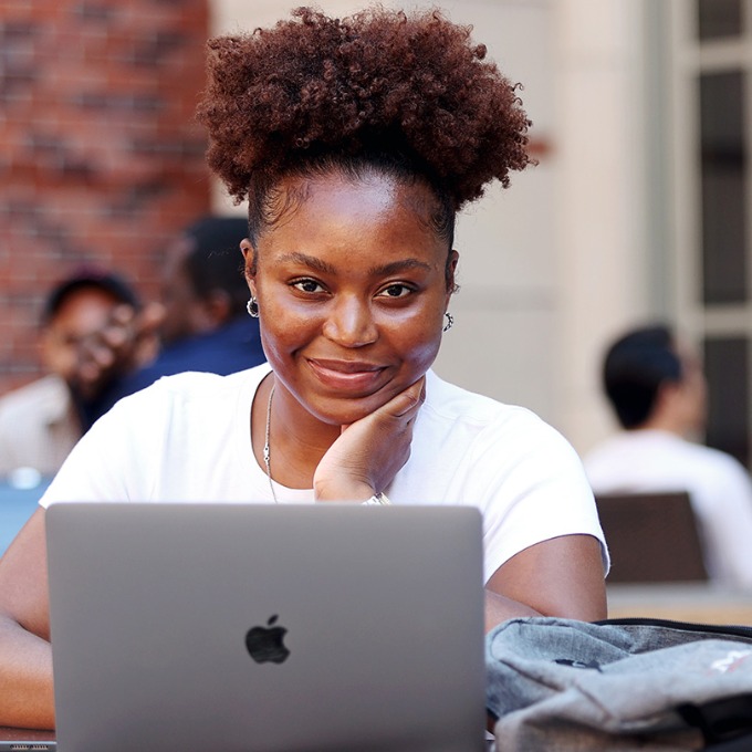 Color photograph of a USC Marshall student seated at a table with their laptop.