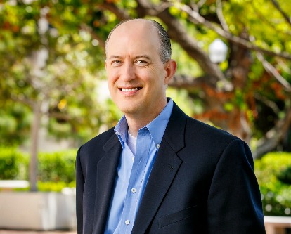 White man in blue suit standing outdoors