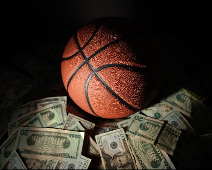 A basketball on a pile of money on dark background