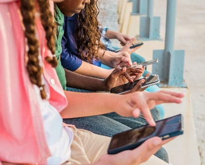 Close-up of teenage friends using mobile phone outdoors