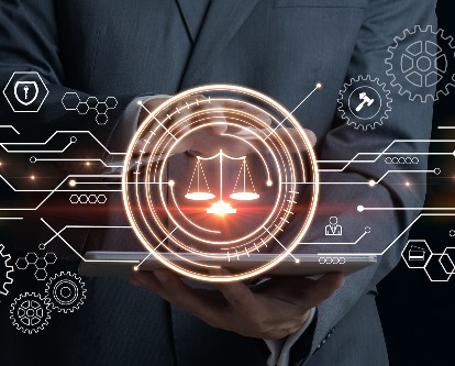 Illuminated scale of justice on a simulated digital background; male holding laptop hidden behind graphic overlay.