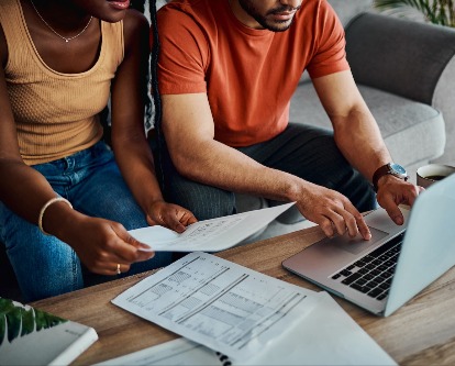 Unknown couple review finances and bills over their computer.