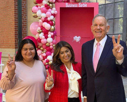 Kimberly Carbajal, Maria Romero-Morales, and Bill Holder give the Fight On sign in front of the Barbie box