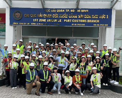 Students pose in front of a Vietnamese sign and do the Fight On Symbol