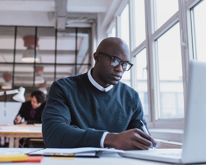 A student working at a desk and laptop.