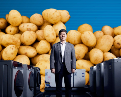 A man standing in between washing machines surrounded by potatoes
