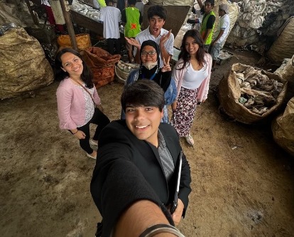 Students pose for a selfie in front of a plastics project.