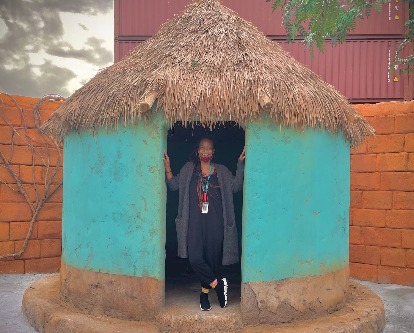 Color photograph of Hannah Beachler posing in a hut on set.