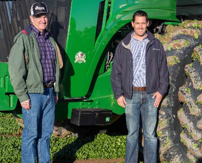 Two Men Standing By a Green Tractor