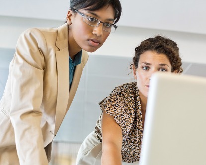 Color photograph of two people looking at a computer screen.