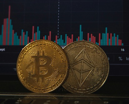 Two bitcoin sitting on a laptop displaying a graph.