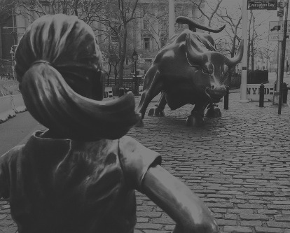 Black and white photograph of the Wall Street Bull as seen looking over the shoulder of the &quot;Fearless Girl&quot; statue.