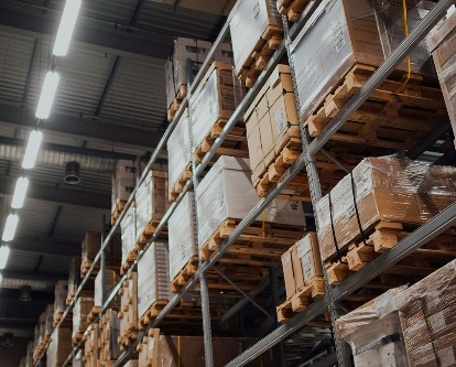 Color photograph inside a warehouse looking up to pallets filled with boxes.