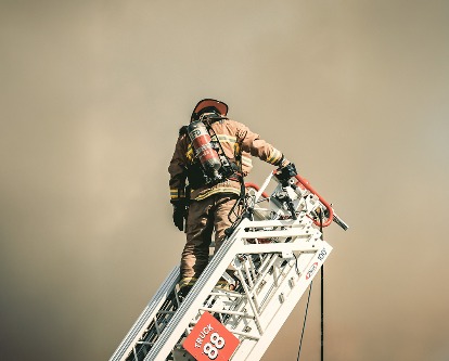 Firefighter on a crane looking down at smoke.