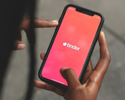 Female hands holding a phone with the Tinder app open.